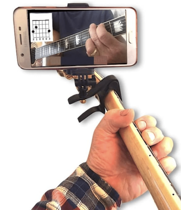 gift ideas of musicians - Close-up of a person holding a guitar neck with a capo and smartphone attached, displaying a chord diagram on the screen—a perfect gift idea for musicians seeking inspiration.