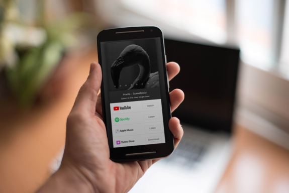 Guitar wall display with various acoustic guitars, bright indoor lighting, and a person holding a colorful arrow sticker for creative social media content.