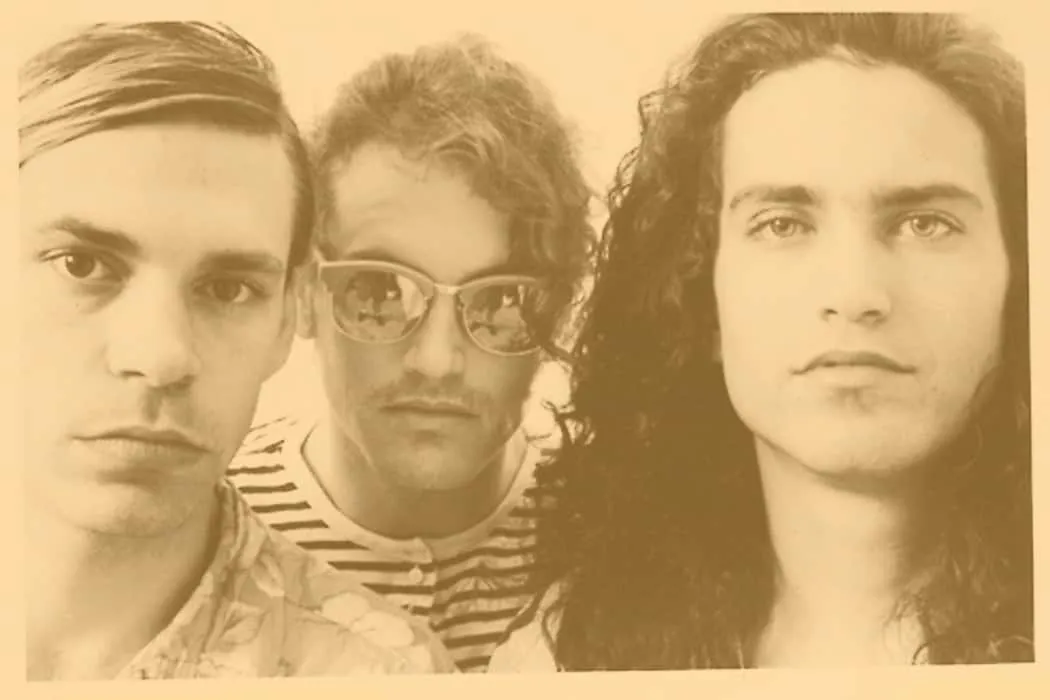 Vintagestyled black-and-white photo of three young men with serious expressions, emphasizing their unique hairstyles and fash