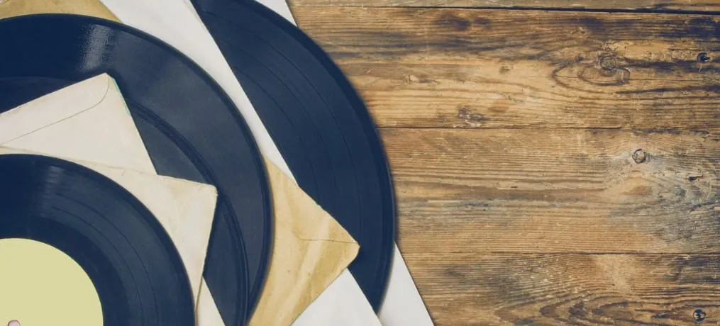 Records of vintage vinyl records on wooden table for music industry and collector interest.