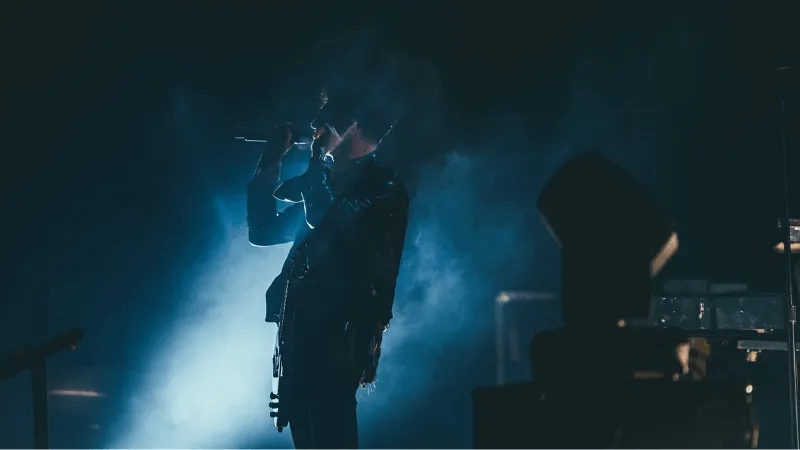 Music artist performing live on stage with dramatic lighting, capturing the essence of the music industry and concert experie