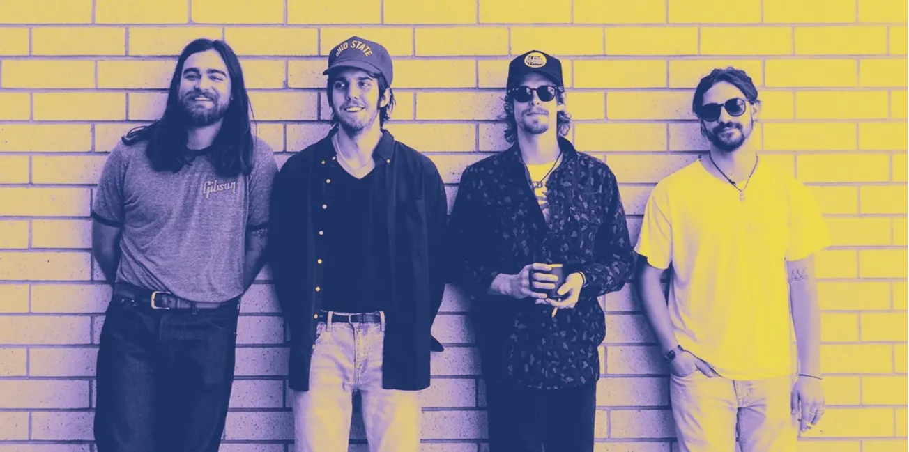 Young indie band members standing against brick wall, relaxed music scene, casual style, vibrant atmosphere, modern musicians