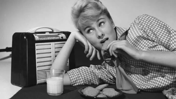 Disoriented woman with vintage radio, glass of milk, and cookies, illustrating retro style and nostalgic theme in black and w