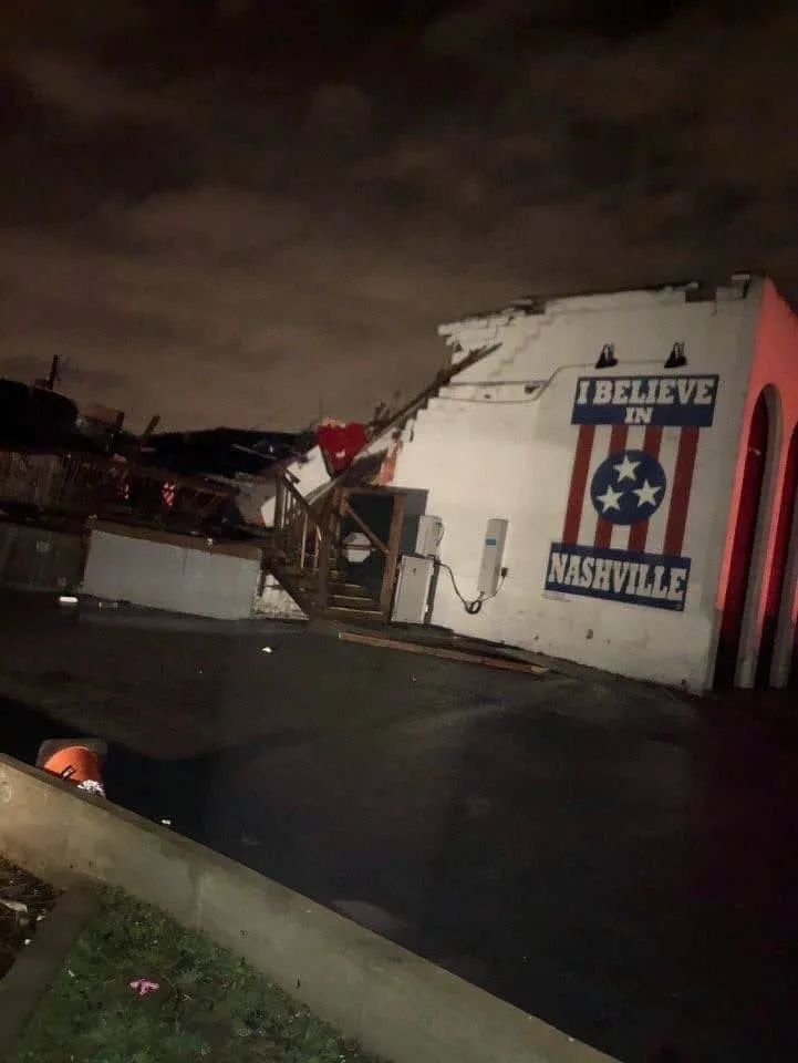 Damaged building with "Believe in Nashville" mural and Tennessee flag design, showing structural destruction and debris after