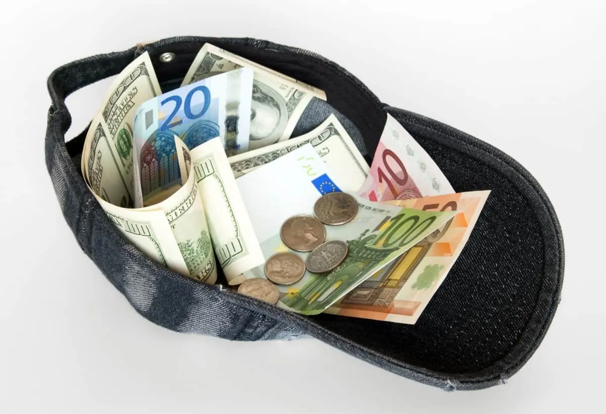Rolled cash and euro coins in black coin pouch, financial savings and money management concept.