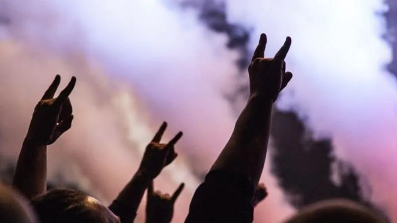Peaceful protest, hands making victory or peace signs against a smoky sky during a demonstration or rally.
