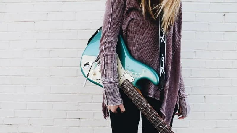 Electric guitar and backpack on a person against white brick wall, music, musician, alternative, indie, artist lifestyle, Hyp