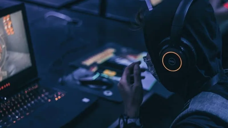 A person wearing headphones working at a laptop with music production equipment, highlighting digital music creation, DJing,