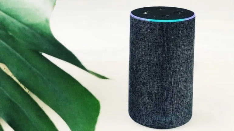 Amazon Echo smart speaker with fabric design on a white surface, activated with blue ring light, emphasizing smart home techn