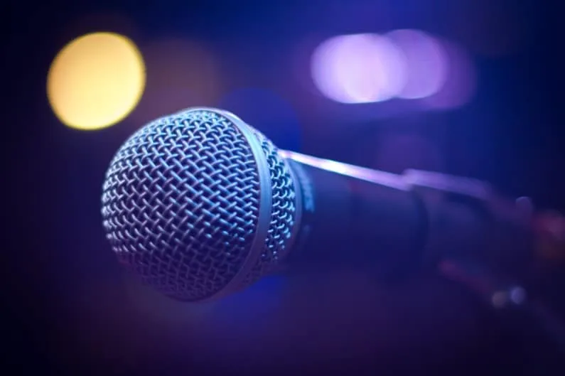 Shure microphone on stage with colorful blurred lights in the background, ready for live performance or podcast recording.