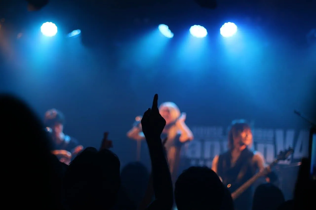 A vibrant concert scene with musicians performing on stage under blue lighting, with audience members enjoying the live music