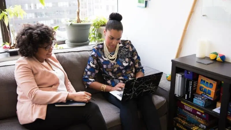 Business women collaborating or discussing on a laptop in an office setting, representing digital media, content creation, or