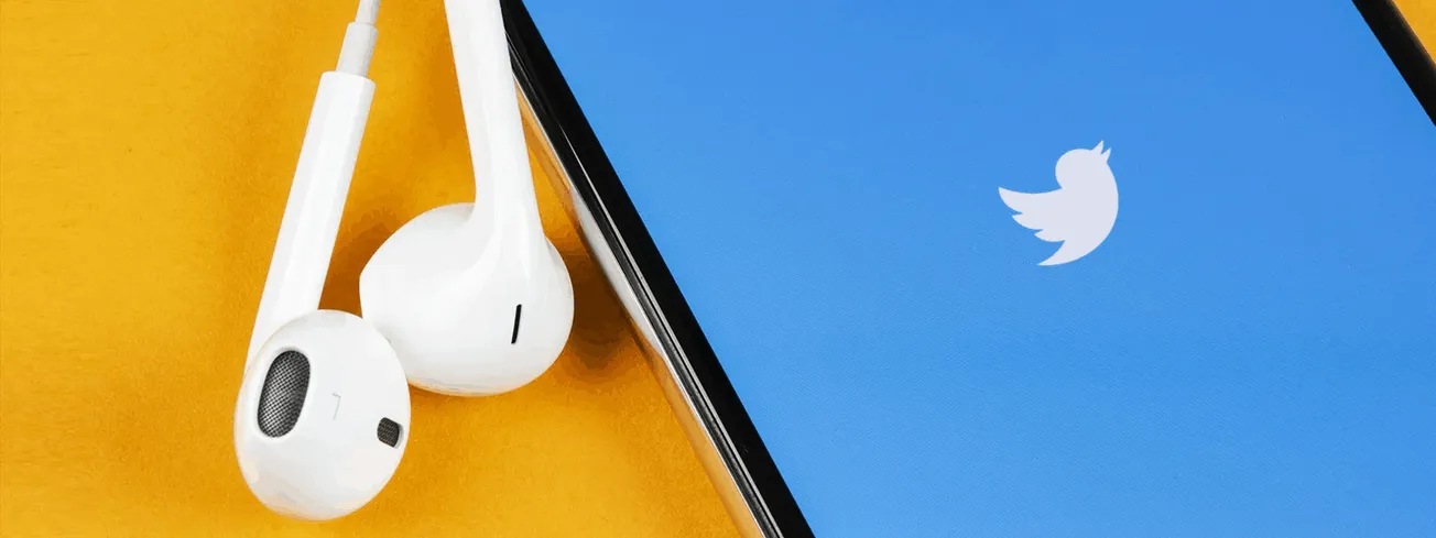 White earphones and a smartphone displaying the Twitter logo, representing social media and digital music promotion.