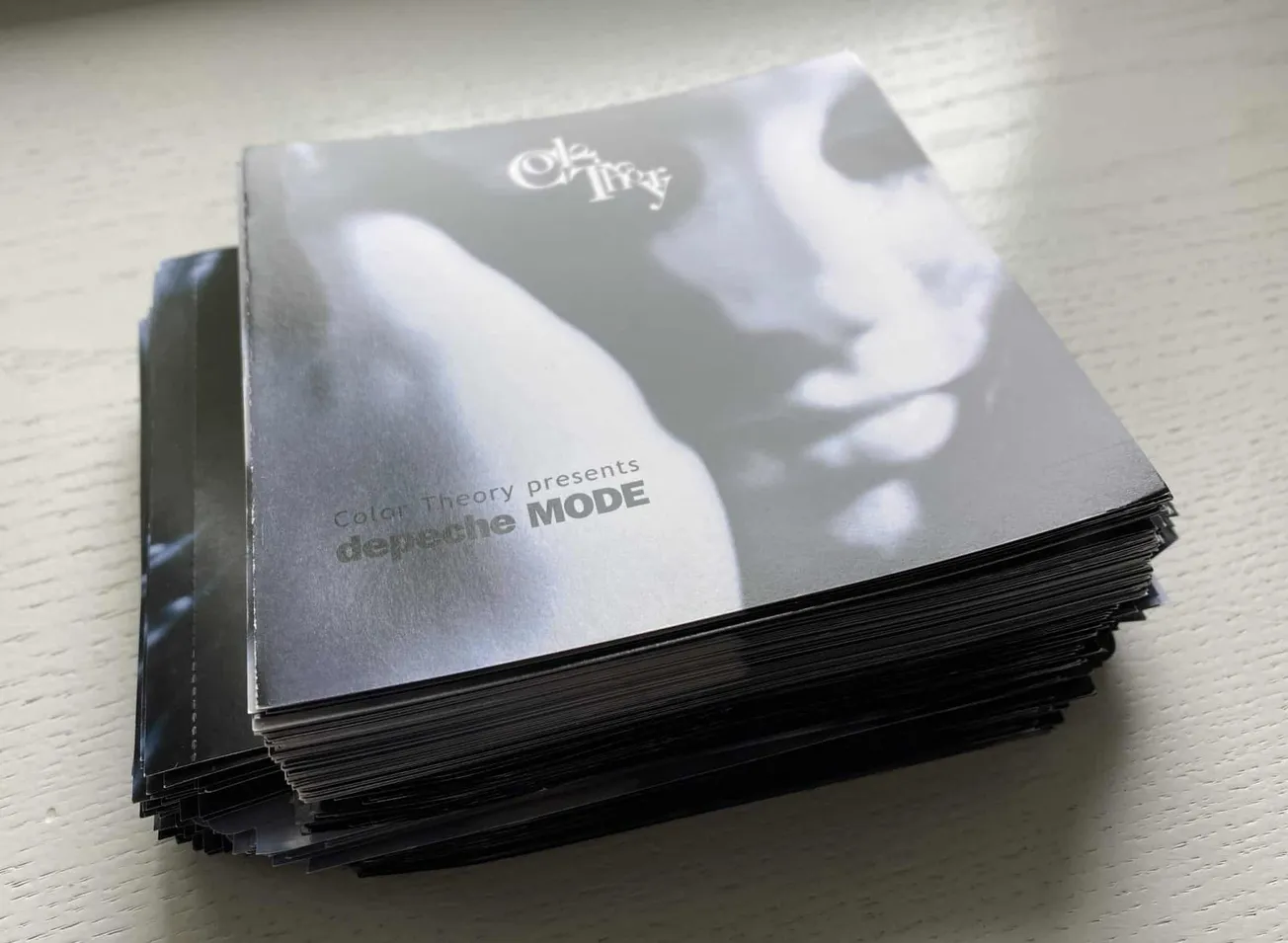 Stacks of promotional cards for the electronic music group Depeche Mode, featuring black and white artwork and bold text, on