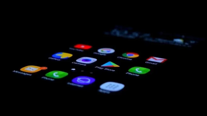 App icons on a smartphone screen illuminated in dark lighting, highlighting various digital applications and services, releva