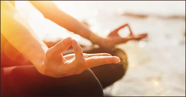 Silhouette of a person practicing yoga or meditation on the beach during sunset, focusing on mindfulness and wellness.