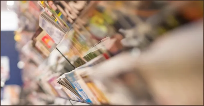 Magazine rack with various magazines and newspapers at a bookstore or newsstand.