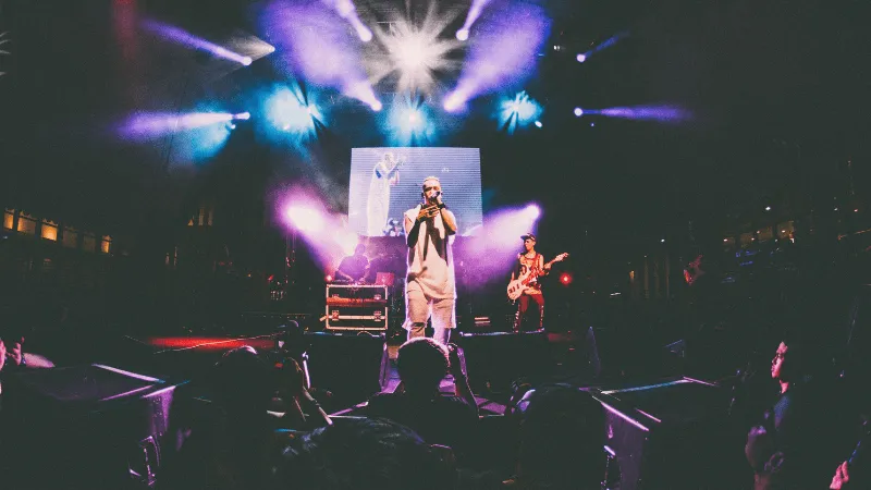 Concert performance at a live music event with stage lighting and band members playing guitars and singing on stage, showcasi