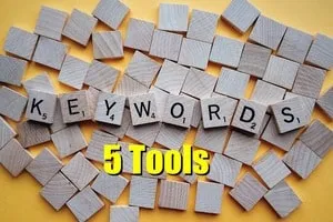 Scrabble tiles spelling "KEYWORDS" with "5 Tools" overlay, surrounded by small wooden blocks, highlighting strategies for SEO