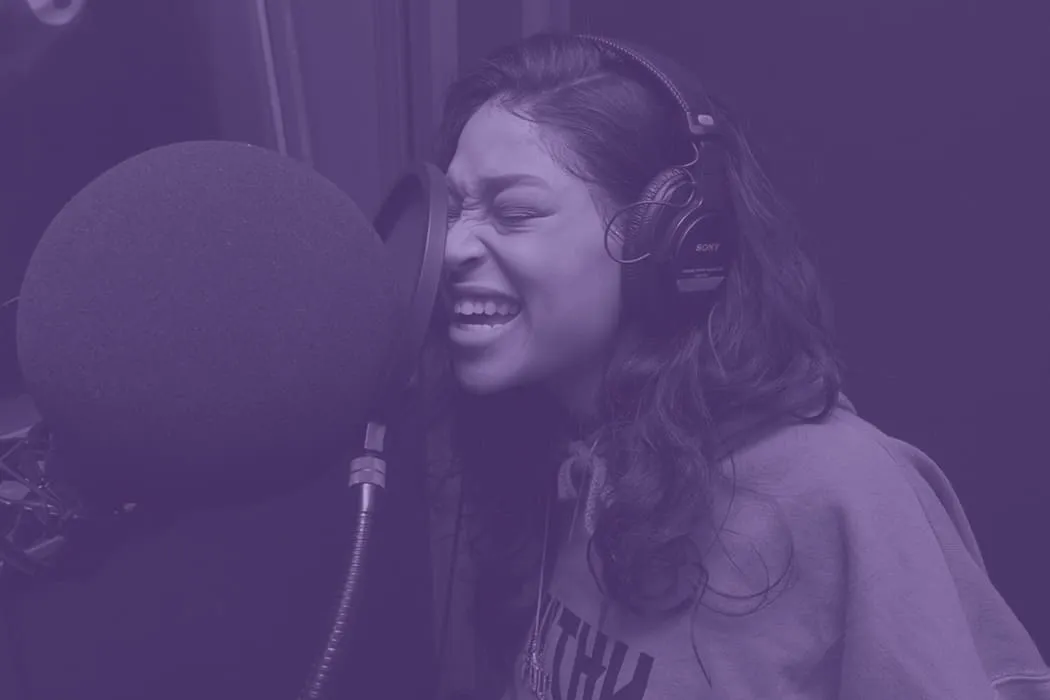 Female singer recording vocals in a professional studio with headphones, capturing high-quality audio for music production.