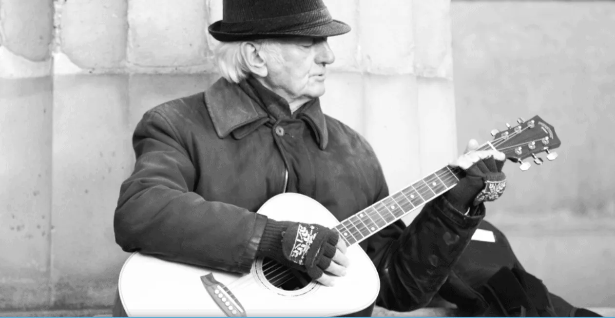 Elderly man playing acoustic guitar on street, black and white music performer street musician outdoor music art cultural sce