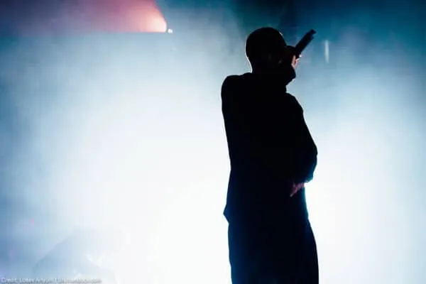 A silhouetted singer performing on stage with dramatic lighting and fog effects, highlighting live music and entertainment sc