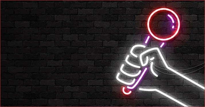 LED neon sign of a hand holding a lollipop against a dark brick wall, illuminated in vibrant pink, red, and white colors, cre
