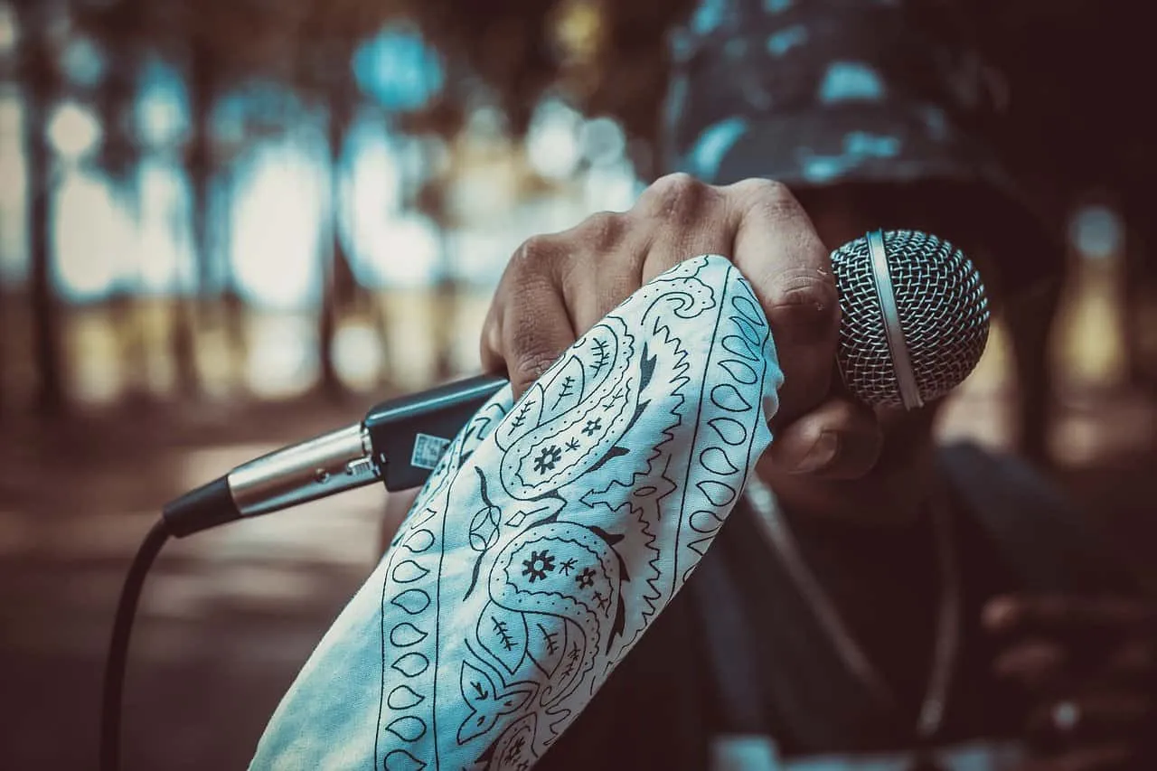 Microphone held by a musician with a tattooed arm, ready for a performance during a music event or concert, with a blurred ou