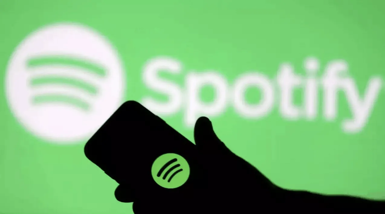 Spotify app on smartphone with blurred Spotify logo in the background, promoting music streaming service.
