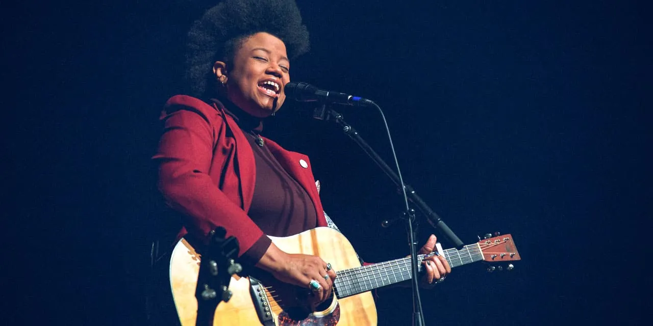 Soulful female musician performing live with acoustic guitar and microphone, showcasing her passion for music and engaging au