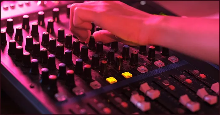 Mixing console with hand adjusting audio levels at a music event or studio, showcasing sound engineering and music production