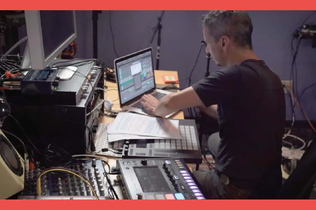 Music production studio with a producer working on electronic music using laptop and MIDI controllers at Hypebot website.