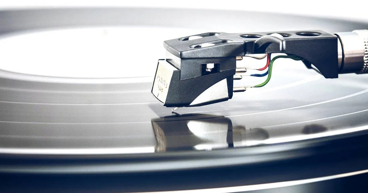 Acrylic turntable with a close-up of a tonearm and stylus capturing a vinyl record, highlighting music playback equipment and