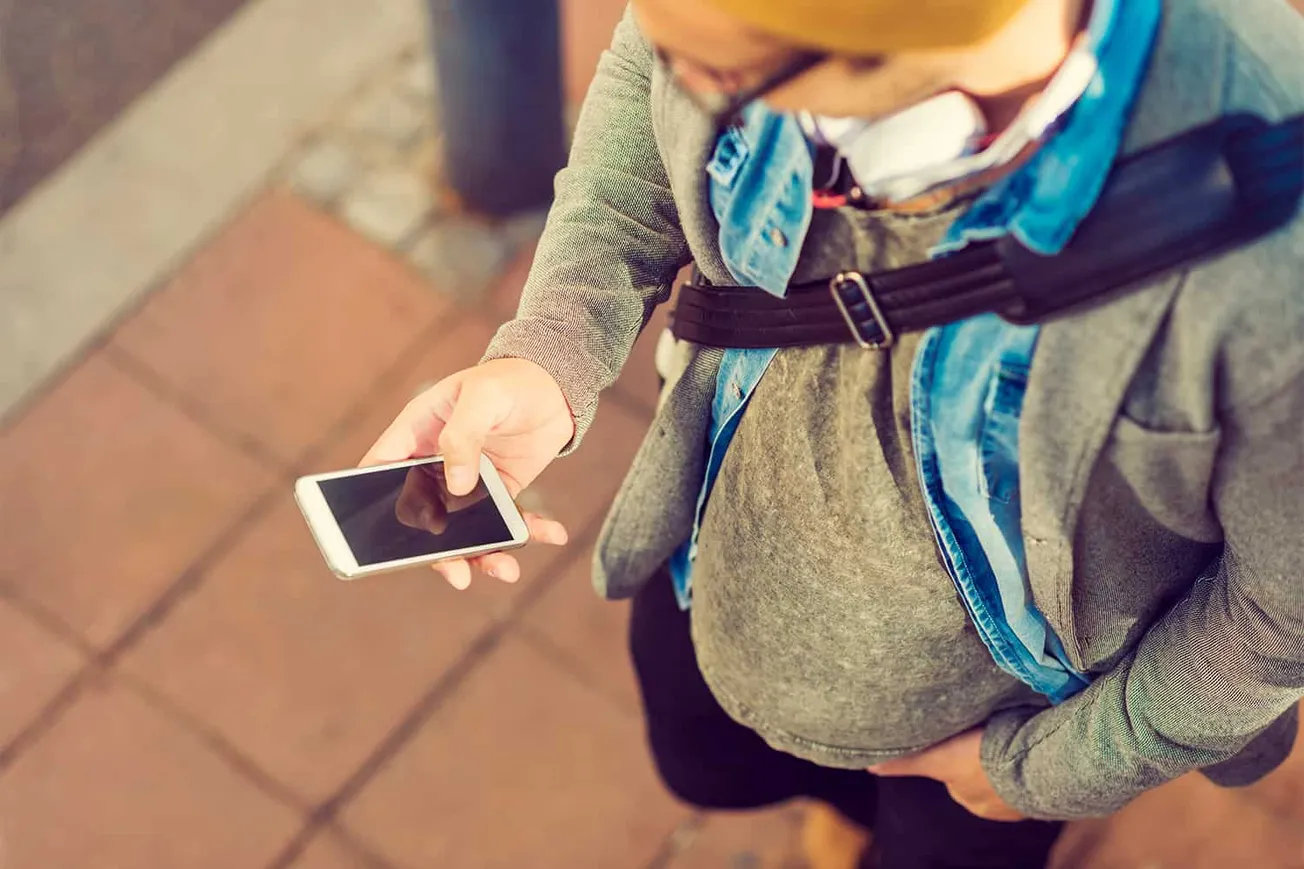 Modern man using smartphone outdoors, standing on city sidewalk with casual clothing, capturing digital trends, social media,