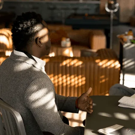 Young professional man sitting at a modern office desk during a business meeting or interview, listening attentively and taki