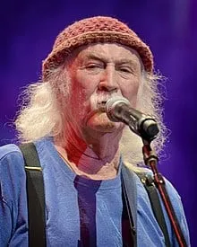 Guitarist with long white hair and a knit cap performing live on stage at a music event, emphasizing rock music and live perf