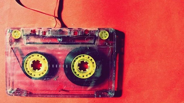 A retro cassette tape on a red background, symbolizing music and audio technology.