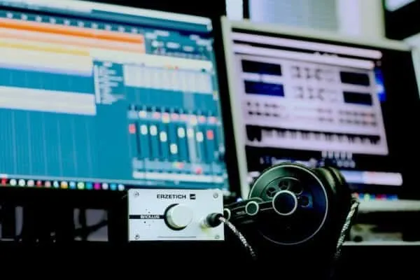 High-tech music production setup with computer monitors, mixing software, and audio equipment for digital music creation and