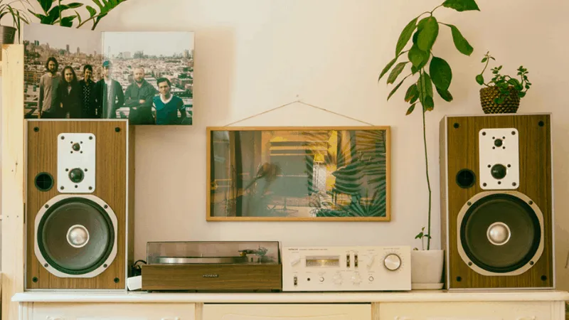 Vintage stereo speakers with a turntable and framed artwork in a cozy home setting, showcasing retro audio equipment and styl