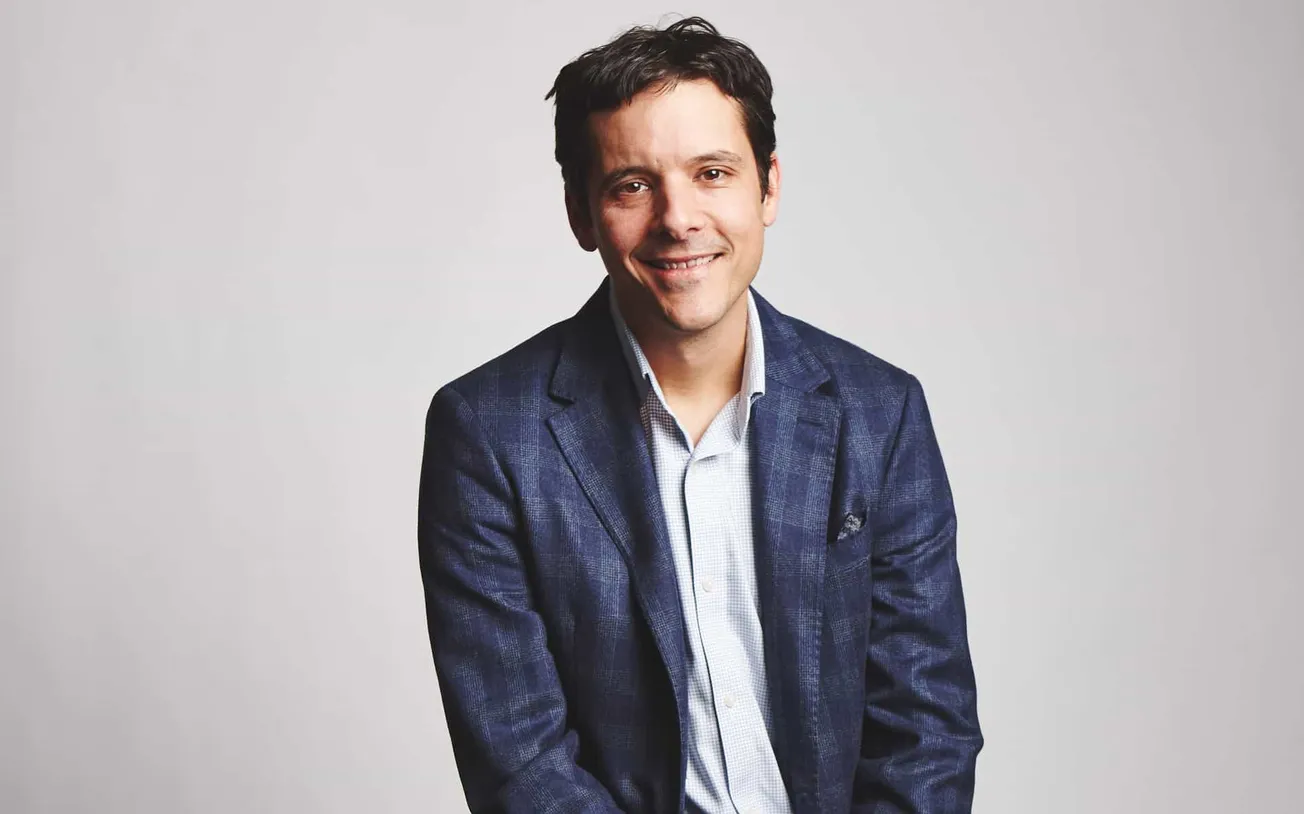 Professional man in a blue blazer smiling, representing music industry expert, influencer, or entrepreneur, with a clean back