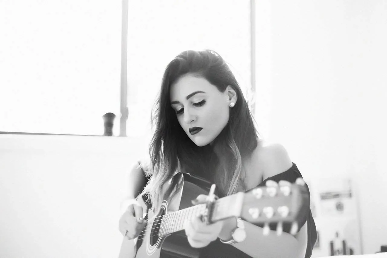 Young woman playing acoustic guitar in black and white studio photo music artist female musician talent musician artist creat