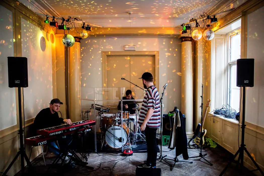 Keyboard, drums, guitar, live music performance, band setup in a cozy indoor venue under disco ball lights.