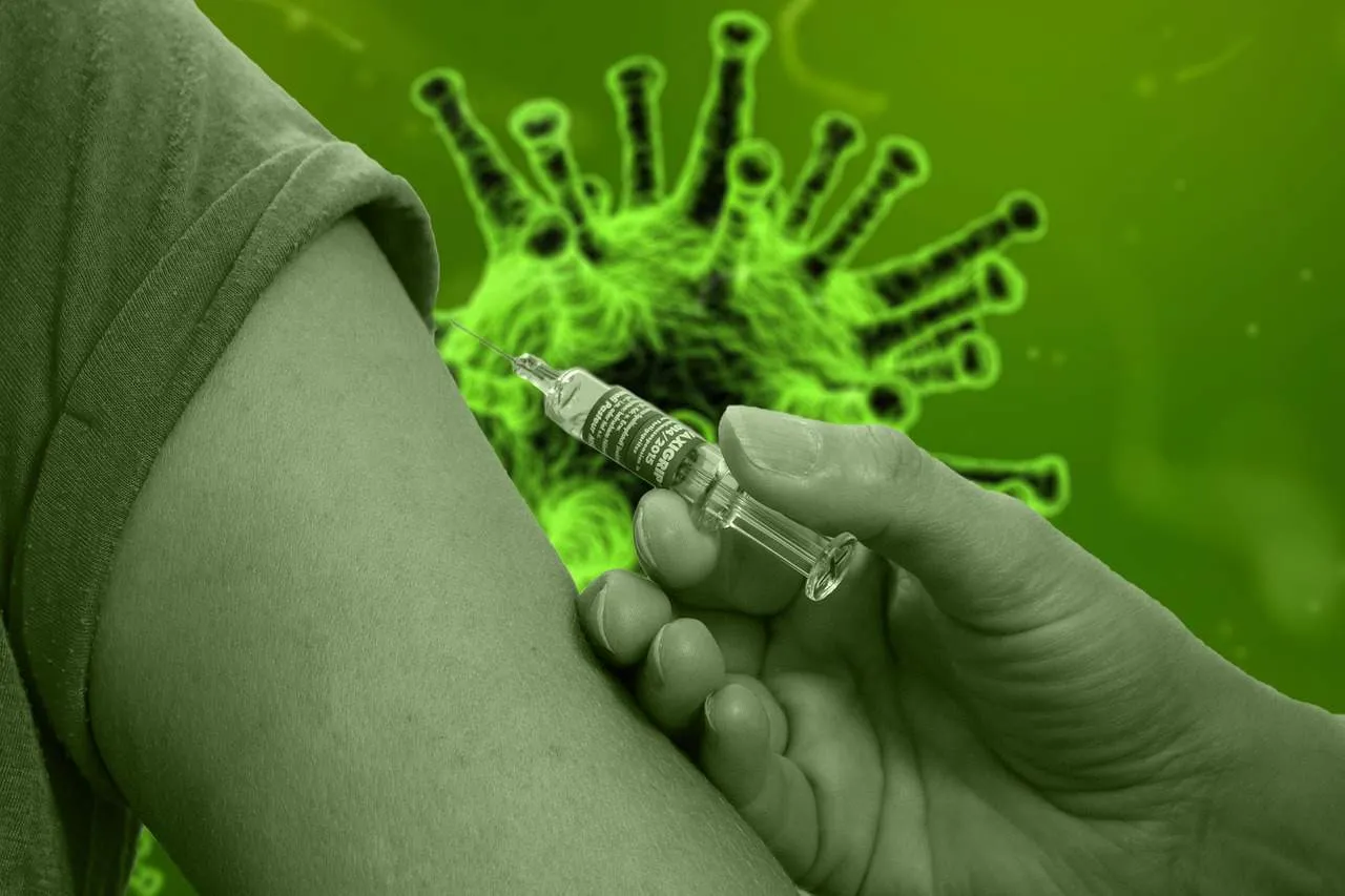 Vaccine injection being administered into a person's upper arm against a digitally illustrated virus background.