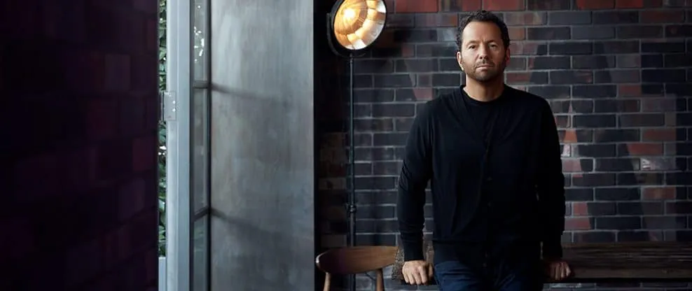 Professional musician artist in black casual clothing sitting in studio with brick wall background, preparing for music produ