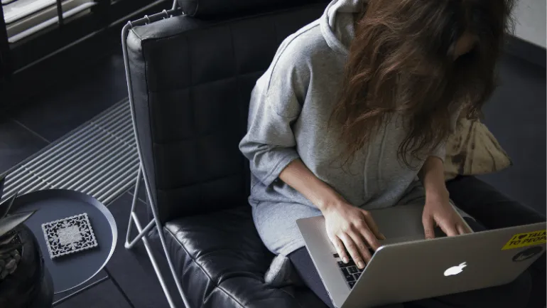 Laptop user working on a silver MacBook in a modern, stylish setting, with a side table and QR code artwork, emphasizing prod