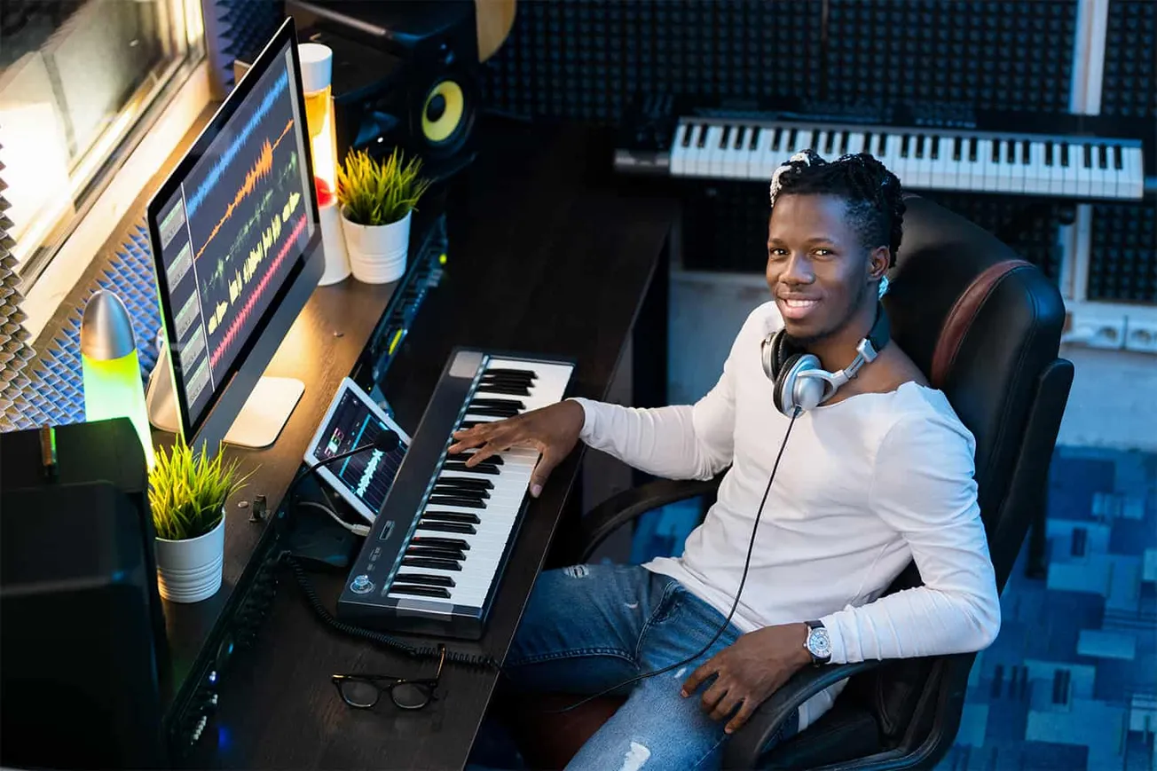 Professional music producer working in home studio with digital audio workstation, keyboard, and computer, focusing on music