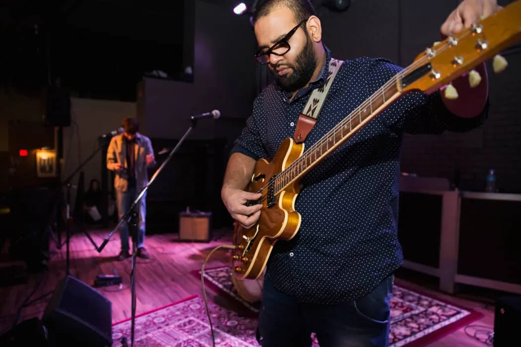 Guitarist performing live on stage at a music venue, capturing a moment of musical expression with professional audio and sta