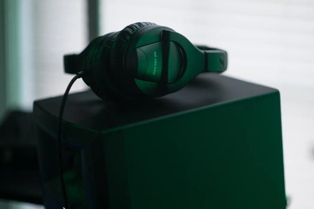 Headphones resting on a computer tower, music production setup, gaming gear, professional audio equipment, black and green he