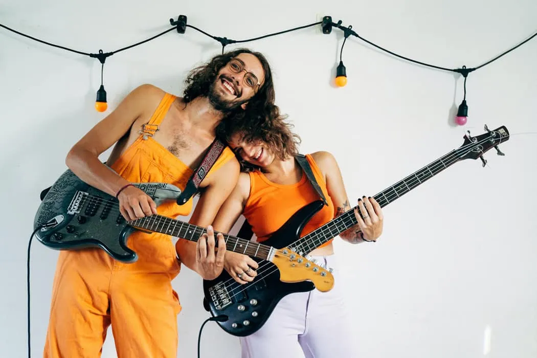 Energetic musicians playing electric guitars during a lively jam session, with colorful string lights in the background, show