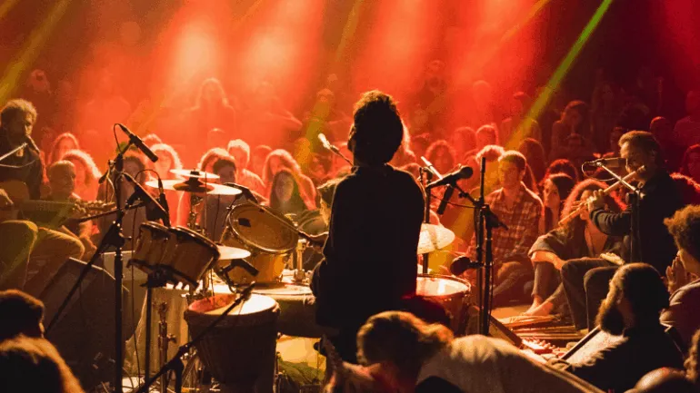 Drummer performing live concert with an audience at a music event, vibrant stage lighting, jazz or rock performance, music fe